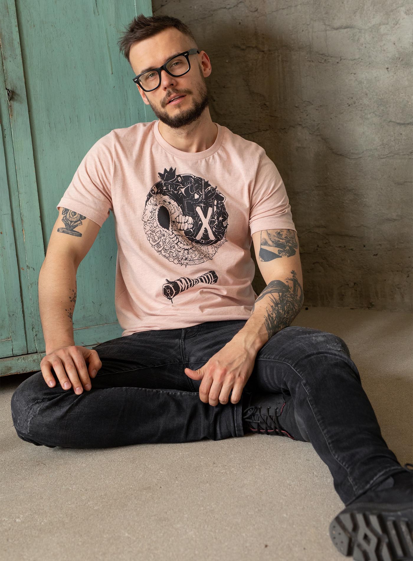 man modeling a heather peach unisex t-shirt featuring a front print of a reinterpretation of the yin yang by Belarusian artist Sasha Sidorovich.