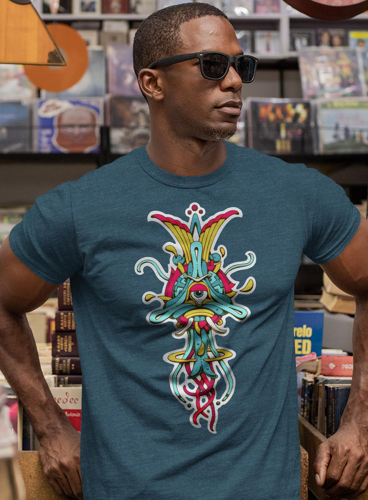 Man modeling a heather blue unisex t-shirt featuring a front print of the Toltec-Aztec goddess of grass illustrated by G.M. Meave