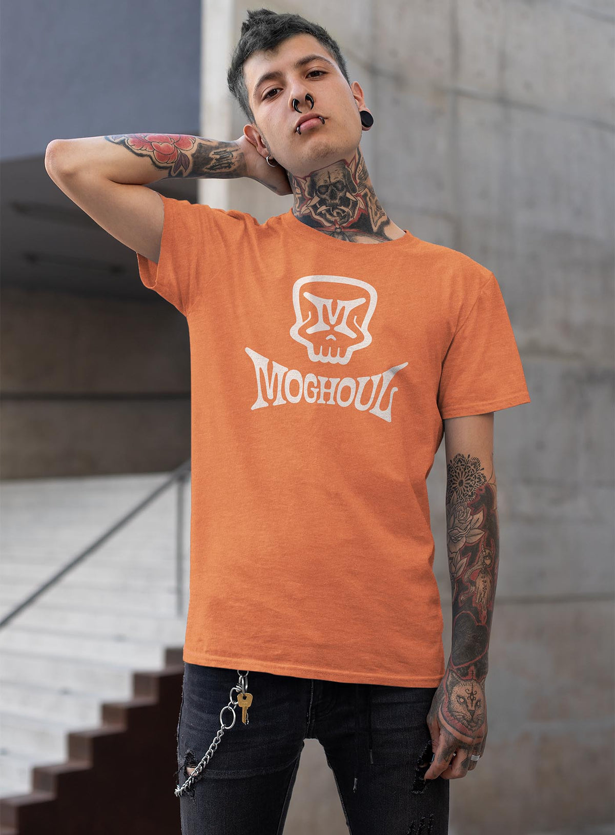 Man modeling a heather orange unisex t-shirt featuring a front print of the Mr. M Moghoul logo by G.M. Meave.
