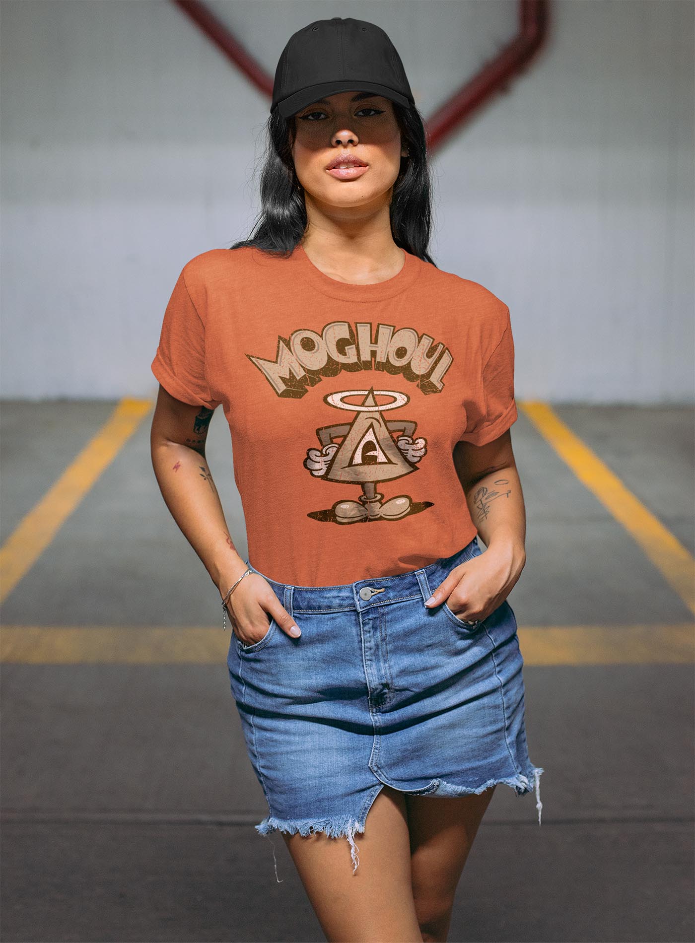 man modeling a yellow unisex t-shirt featuring a front print of a cartoon character based on the mythical Eye of Providence. By Mexican illustrator G.M. Meave.