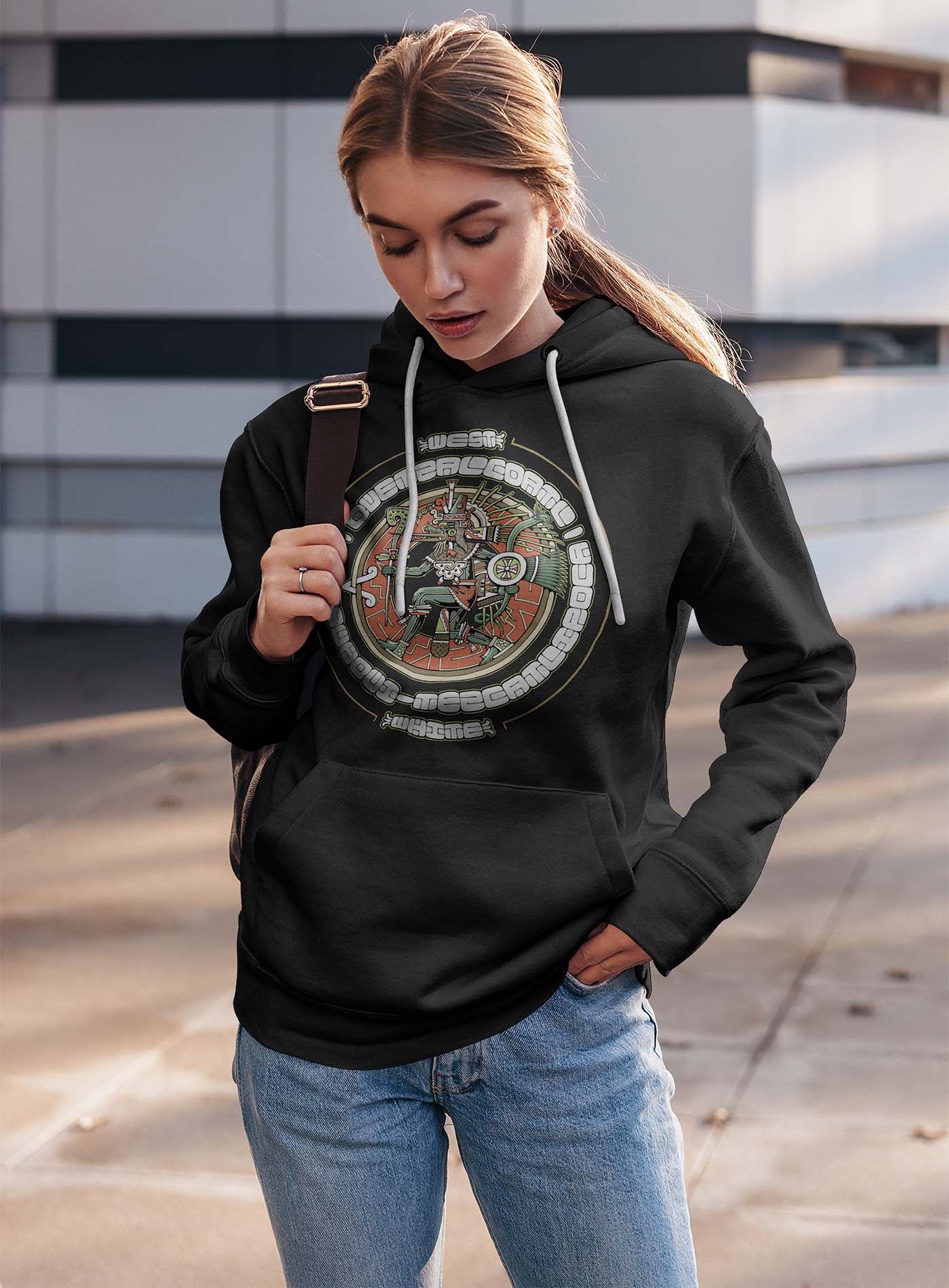 man modeling a black unisex hoodie featuring a front print of the toltec-aztec god Tezcatlipoca also known as Quetzalcoatl. Reinterpretation by Mexican illustrator G.M. Meave.