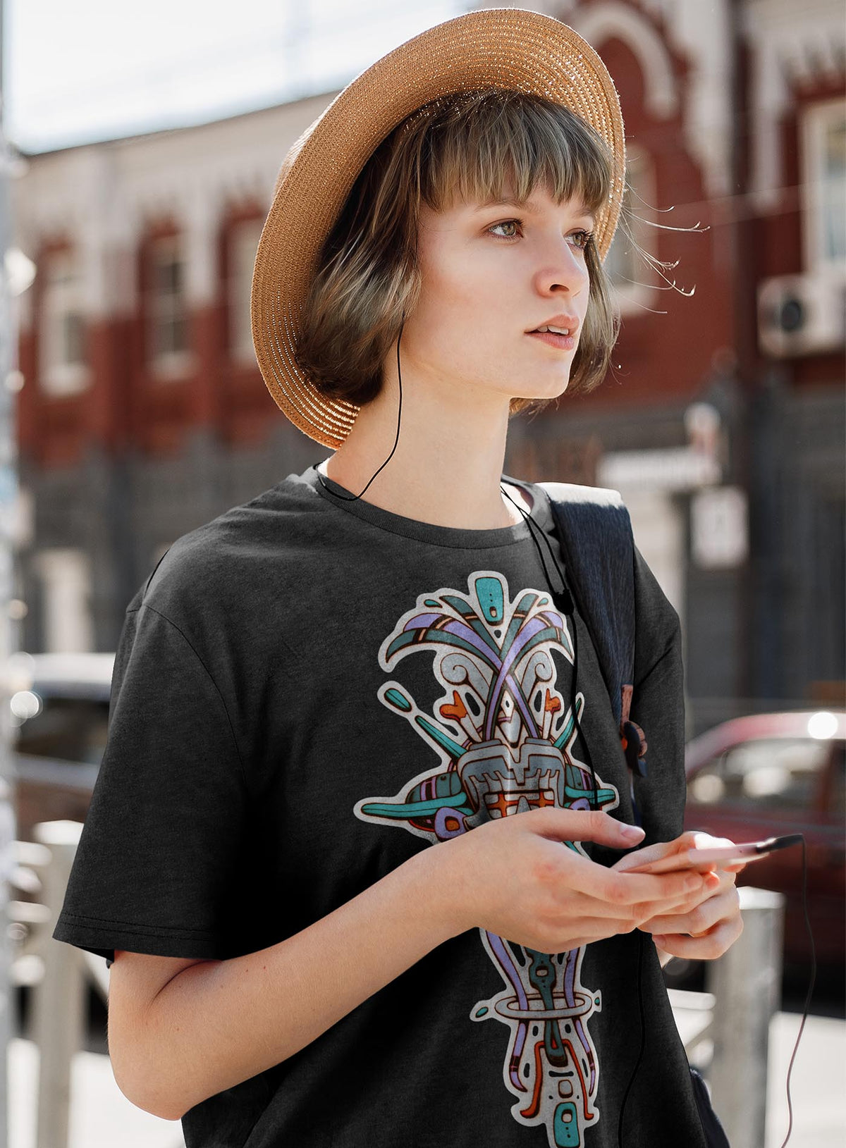 Woman modeling a Heather black unisex t-shirt featuring a front print of Tzontecotl, the Nahua word for skull, associated with a mask that submerged the wearer into the underworld. illustrated by G.M. Meave.