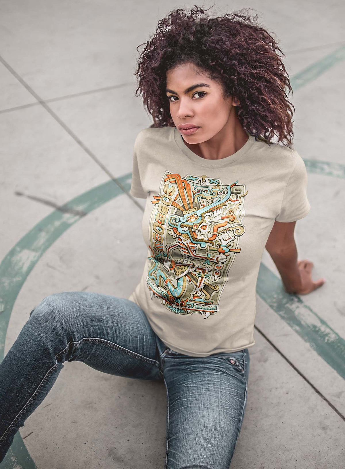 woman modeling a Heather beige unisex t-shirt featuring a front print of the Aztec god Tezcatlipoca illustrated by G.M. Meave.