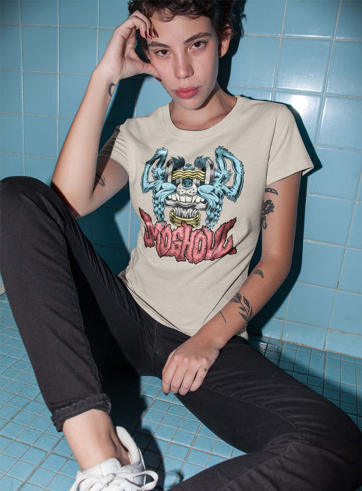 Woman modeling a Heather beige unisex t-shirt featuring a front print of a dog and the Moghoul logo rendered in urban art style by Jason Hankins aka Jazmo.
