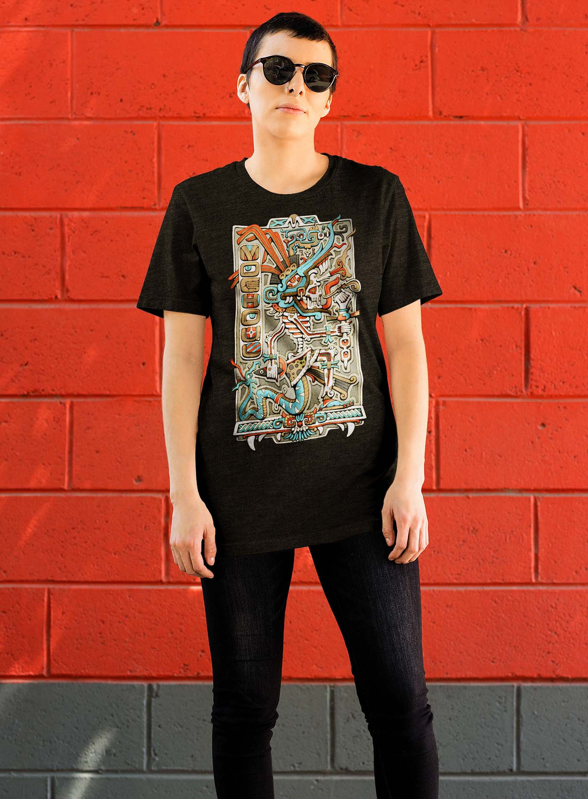 Modeling a Heather black unisex t-shirt featuring a front print of the Aztec god Tezcatlipoca illustrated by G.M. Meave.