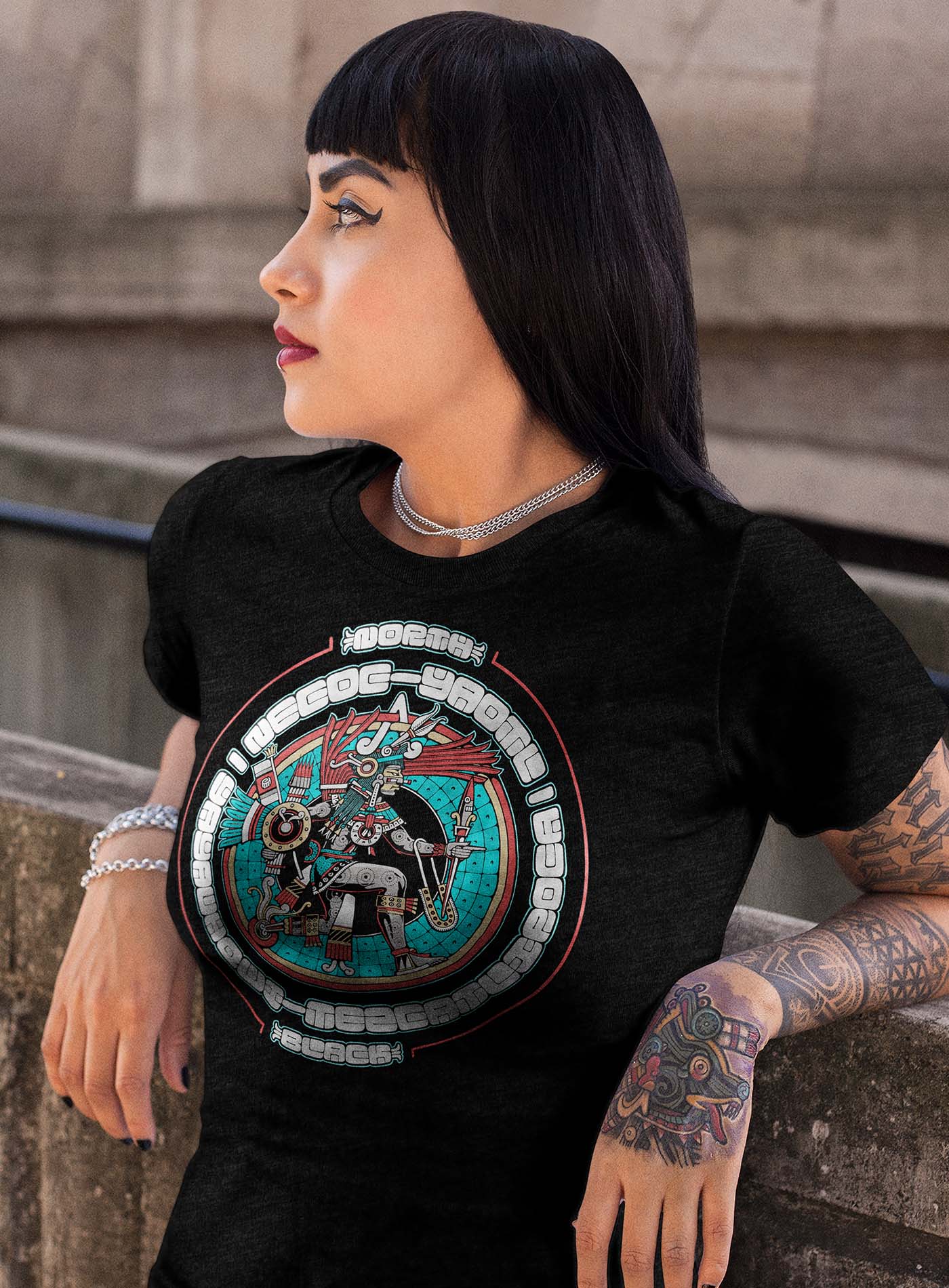 Female modeling a Heather black unisex t-shirt featuring a front print of the toltec-aztec god Yayauhqui-Tezcatlipoca also known as Necoc-yaotl. Reinterpretation by Mexican illustrator G.M. Meave.
