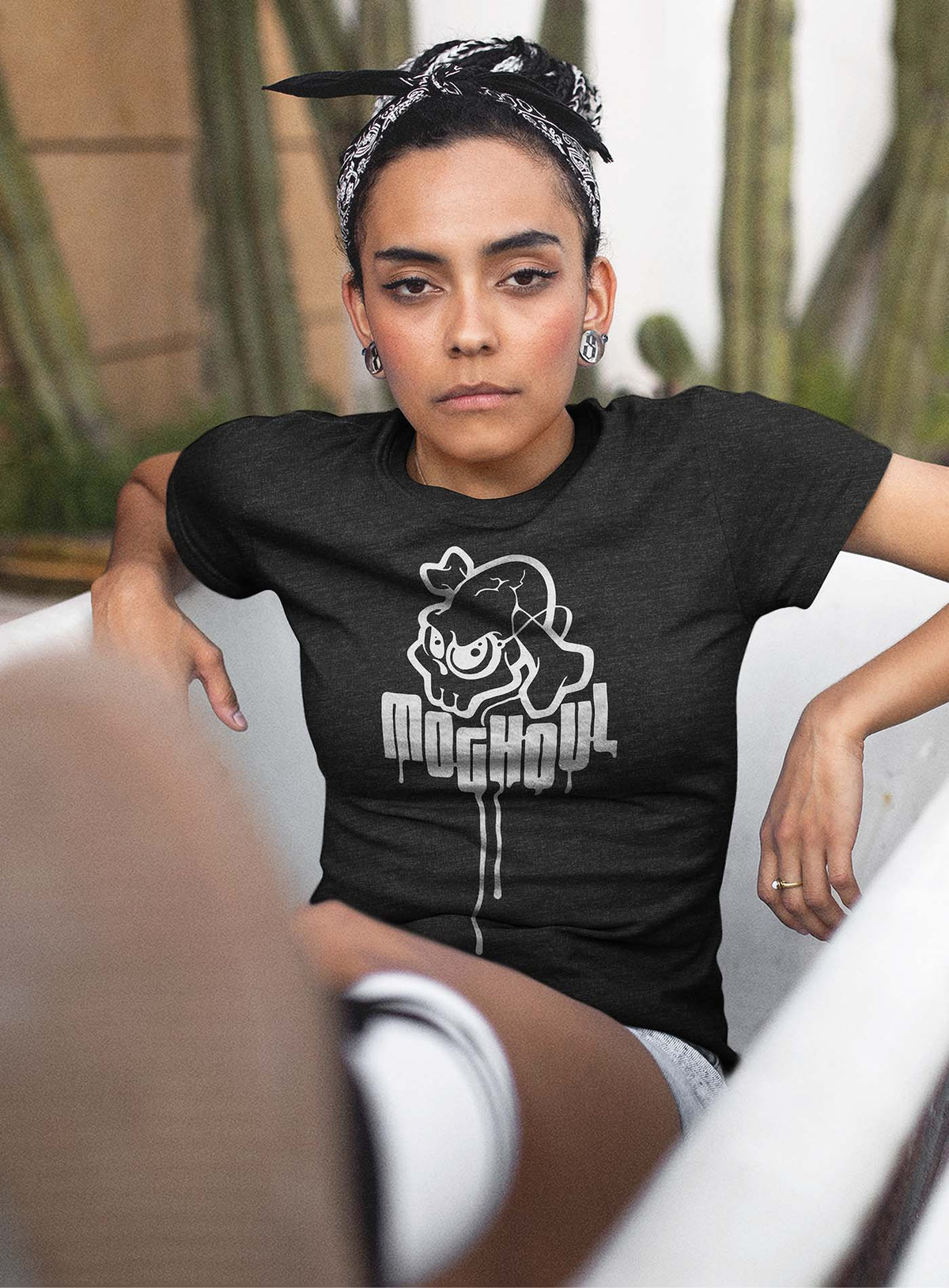 Female modeling a heather grey unisex t-shirt featuring a yellow Mr. Shade Moghoul logo by G.M. Meave.