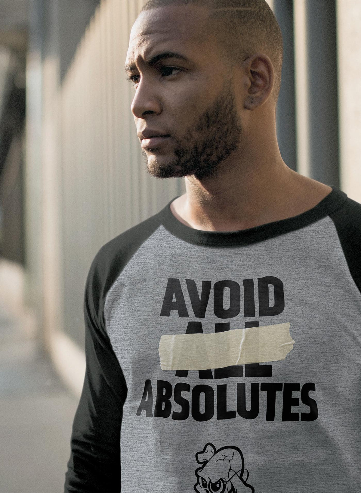 man modeling a Heather grey unisex reglan t-shirt featuring the paradoxical phrase &quot;avoid all absolutes&quot; and the moghoul logo.
