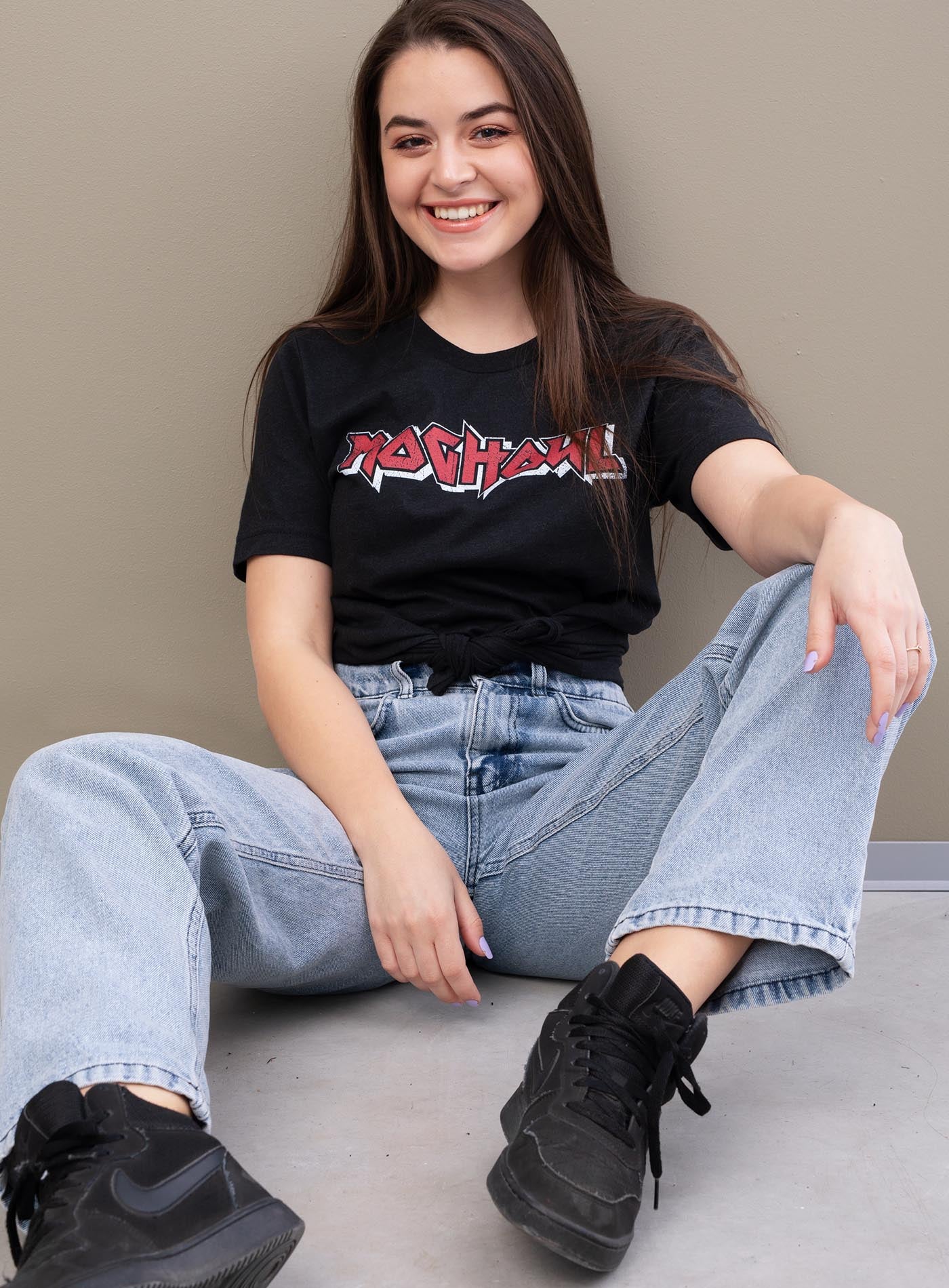 Girl modeling a Heather black unisex t-shirt featuring a front print of the Moghoul logo in vintage 80's hair-band style.