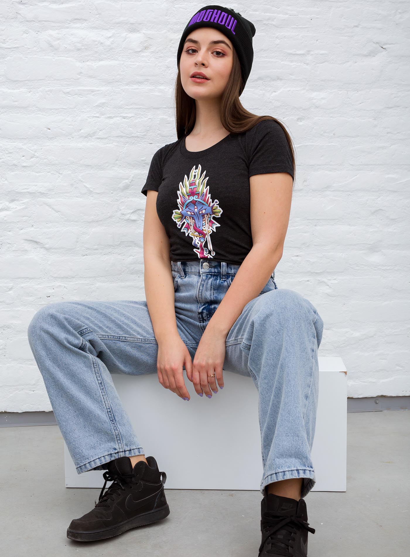 Woman modeling a Heather black woman's t-shirt featuring a front print of the Toltec and Aztec coyote deity illustrated by G.M. Meave.