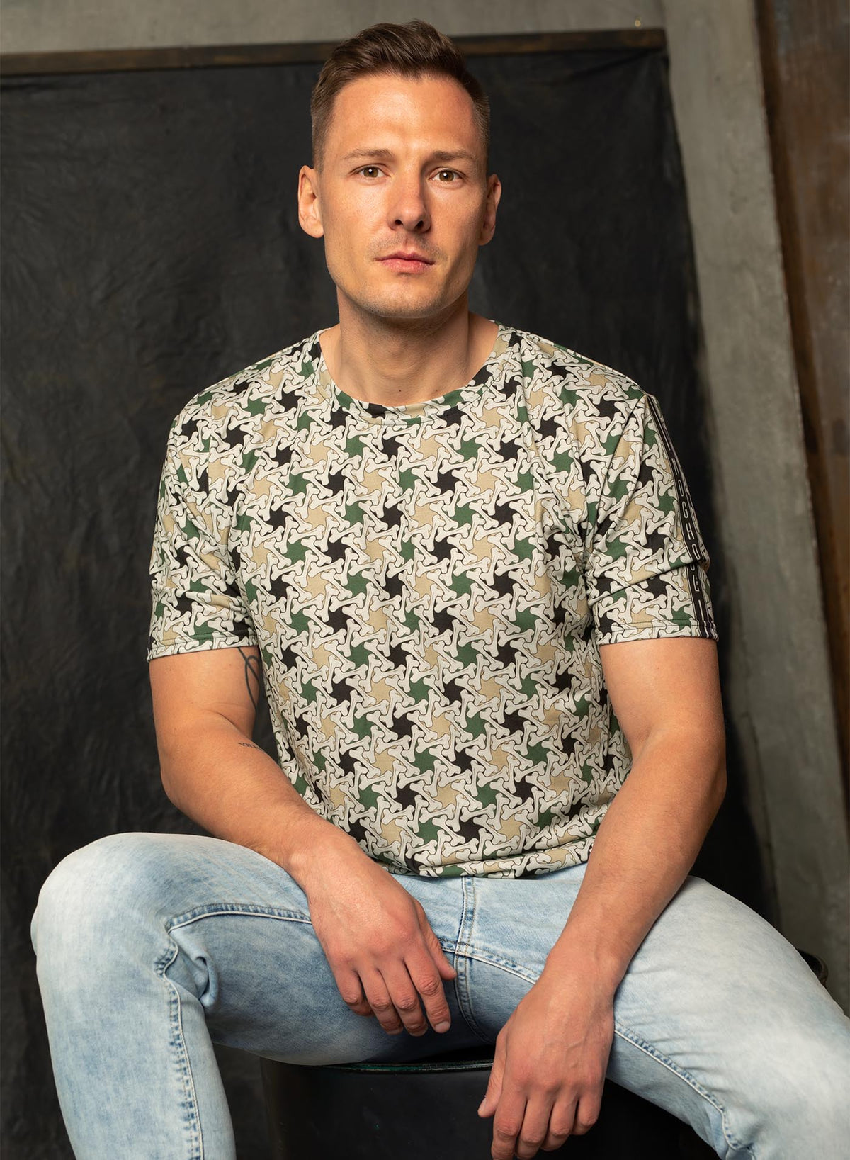 Man modeling an All over dye sublimation t-shirt featuring a patter of bones based on Islamic ornamental art in green colors.