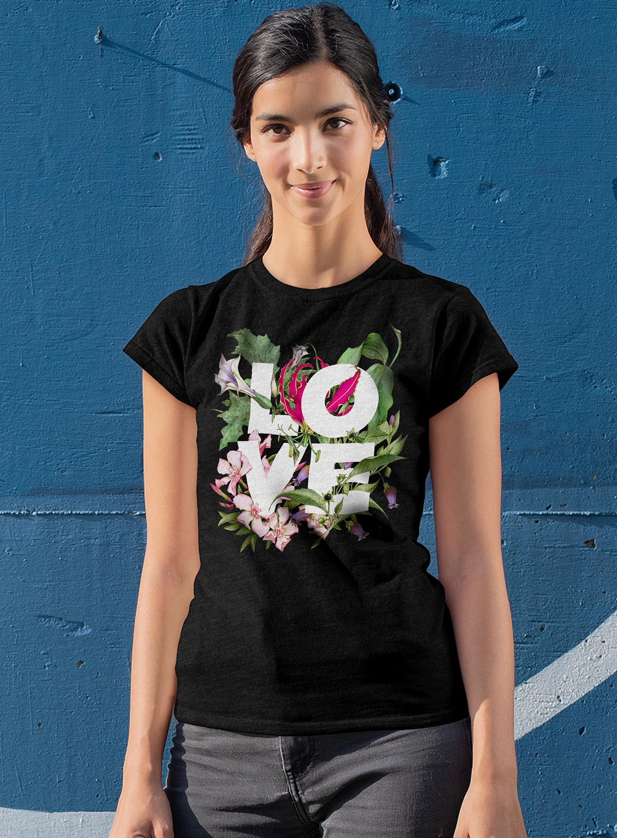 Woman modeling a black woman&#39;s t-shirt featuring the word LOVE surrounded by poisonous flowers such as oleander, fire lily, belladonna and toloache.