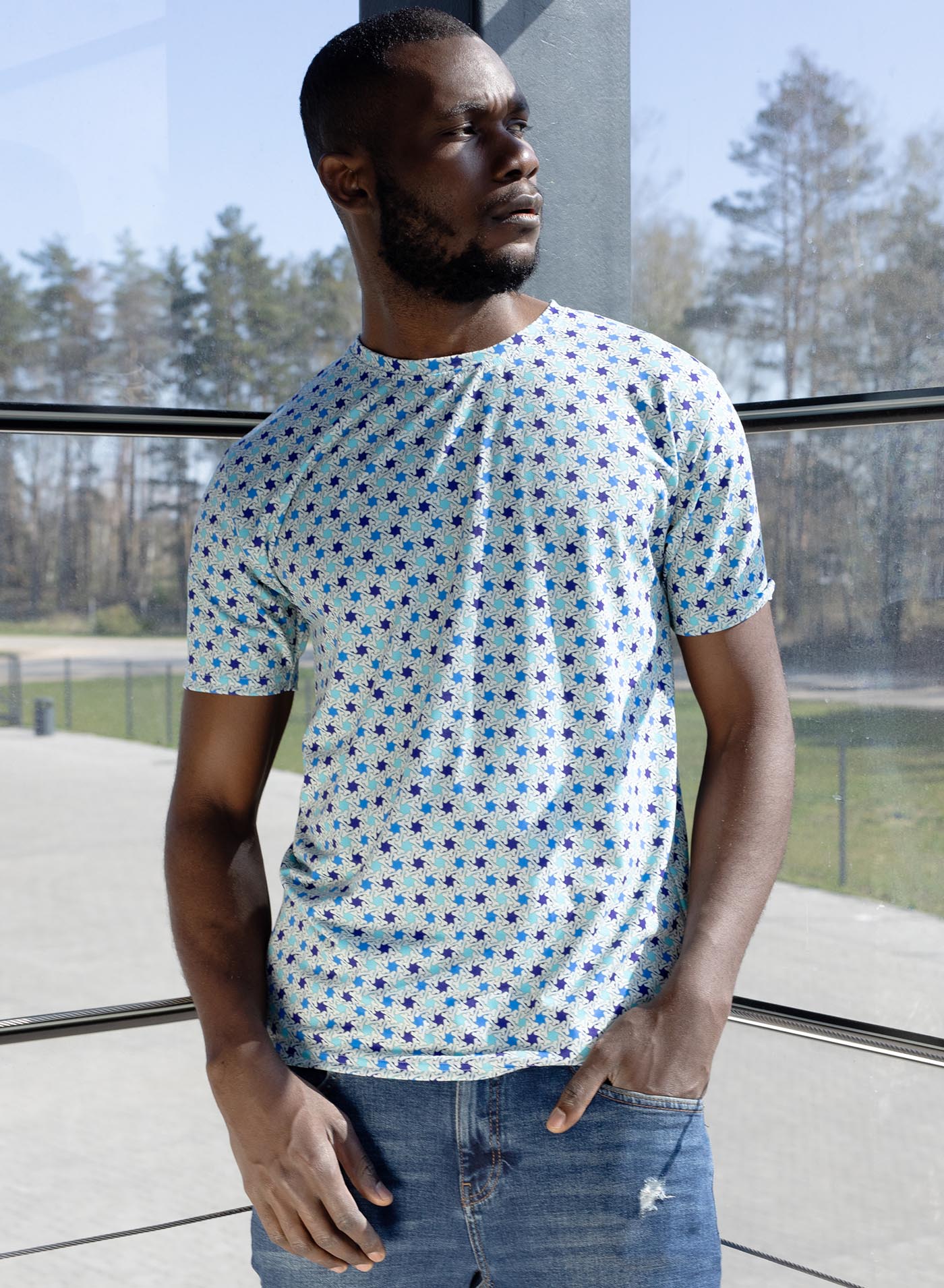 Man modeling an All over dye sublimation t-shirt featuring a patter of bones based on Islamic ornamental art in blue colors.