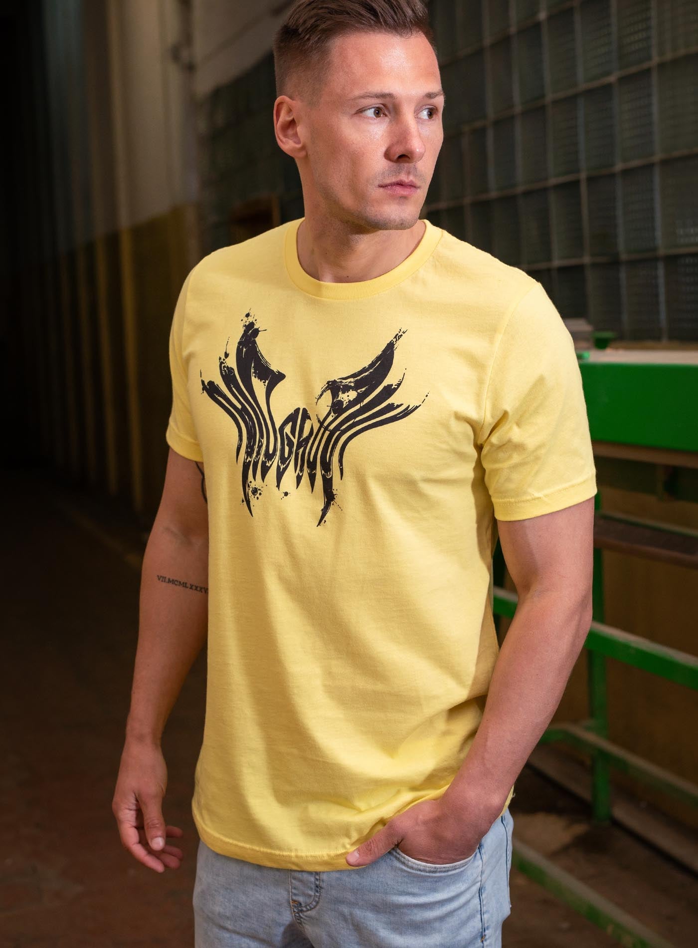 man modeling a yellow unisex t-shirt featuring a front print of the black Mr. Splatter Moghoul logo by Sasha Sidorovich