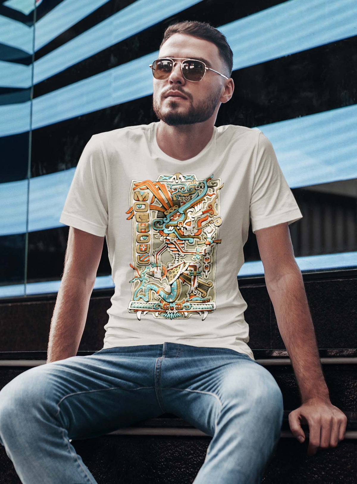 Man modeling a Heather beige unisex t-shirt featuring a front print of the Aztec god Tezcatlipoca illustrated by G.M. Meave.