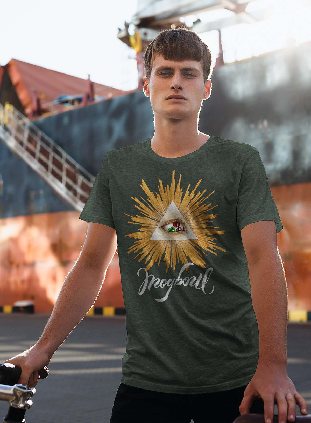 Man modeling a Heather dark green unisex t-shirt featuring a front print of a reinterpretation of the Horus pyramid and Moghoul ambigram logo by G.M. Meave.