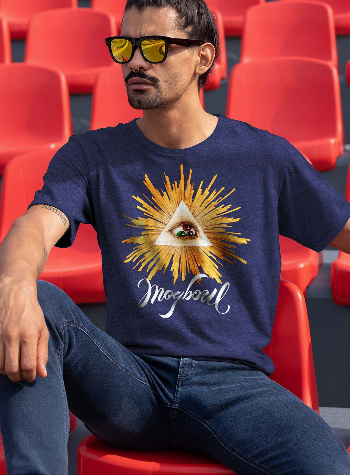 Man modeling a Heather navy blue unisex t-shirt featuring a front print of a reinterpretation of the Horus pyramid and Moghoul ambigram logo by G.M. Meave.