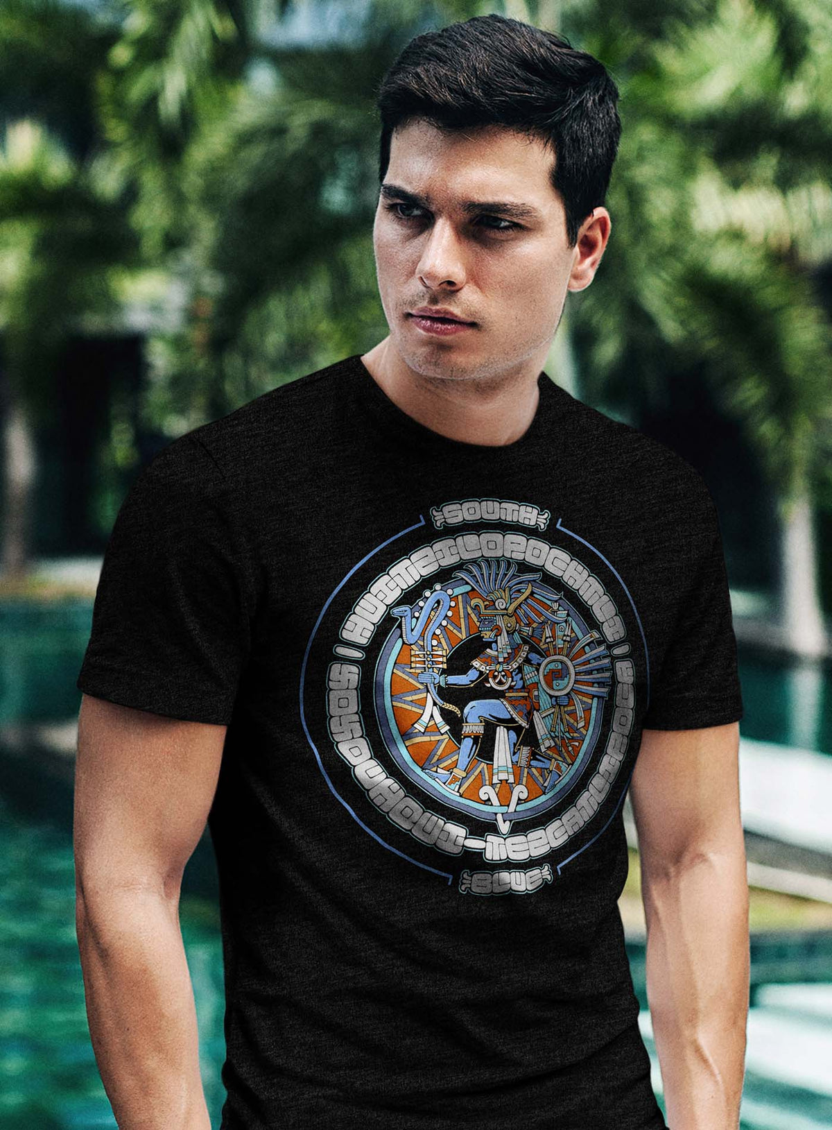 Man modeling a Heather black unisex t-shirt featuring a front print of the toltec-aztec god Tezcatlipoca also known as Huitzilopochtli. Reinterpretation by Mexican illustrator G.M. Meave.