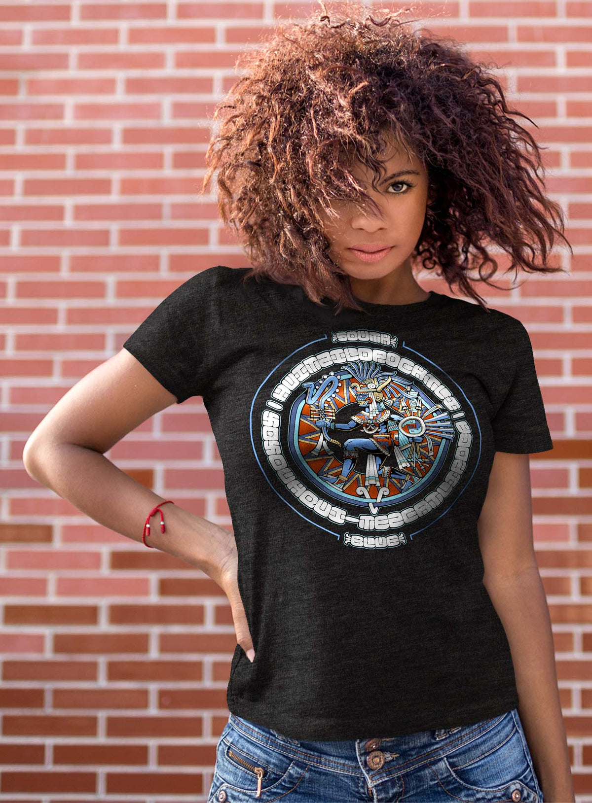 Female modeling a Heather black unisex t-shirt featuring a front print of the toltec-aztec god Tezcatlipoca also known as Huitzilopochtli. Reinterpretation by Mexican illustrator G.M. Meave.