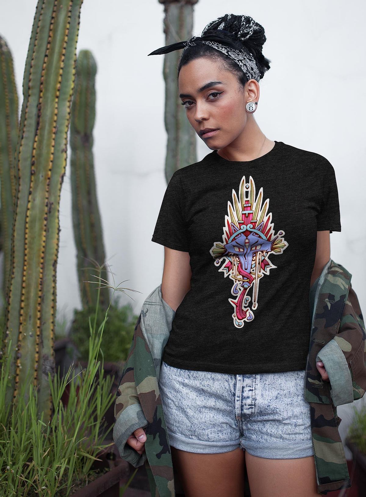 Woman modeling a heather black unisex t-shirt featuring a front print of the Toltec and Aztec coyote deity illustrated by G.M. Meave