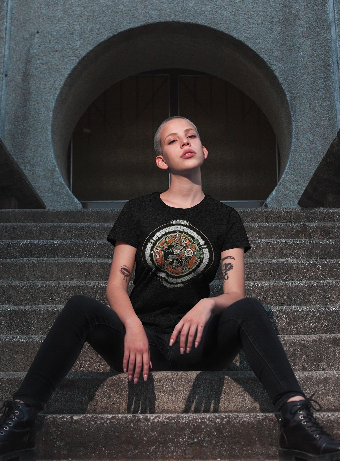 man modeling a Heather black unisex t-shirt featuring a front print of the toltec-aztec god Tezcatlipoca also known as Quetzalcoatl. Reinterpretation by Mexican illustrator G.M. Meave.