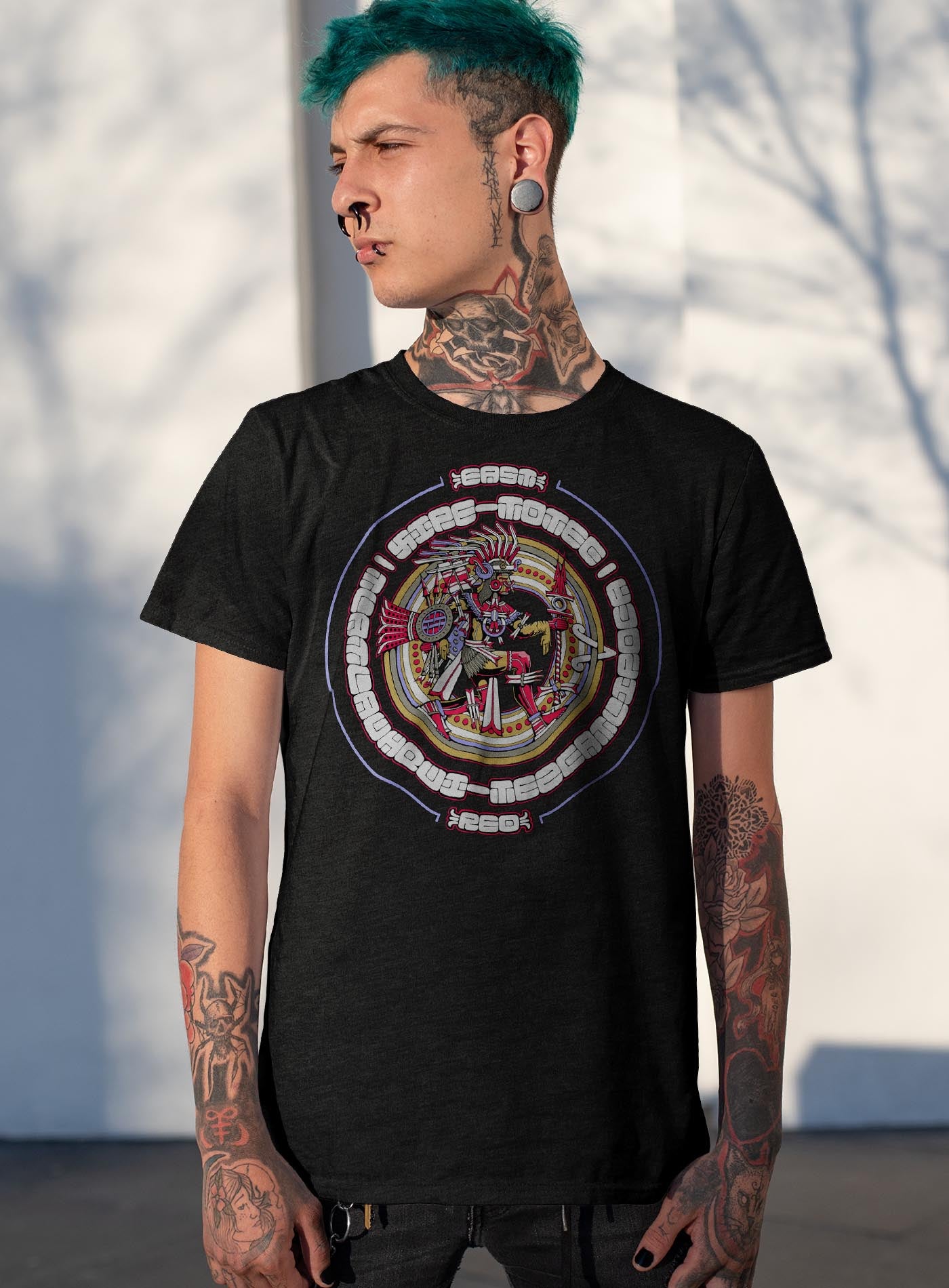 Female modeling a Heather purple unisex t-shirt featuring a front print of the toltec-aztec god Tlatlauhqui-Tezcatlipoca also known as Xipe-Totec. Reinterpretation by Mexican illustrator G.M. Meave.