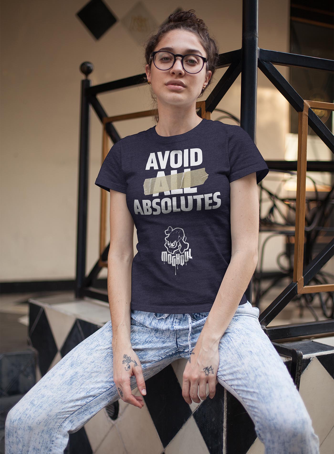 man modeling a heather black unisex t-shirt featuring the paradoxical phrase "avoid all absolutes" and the moghoul logo.