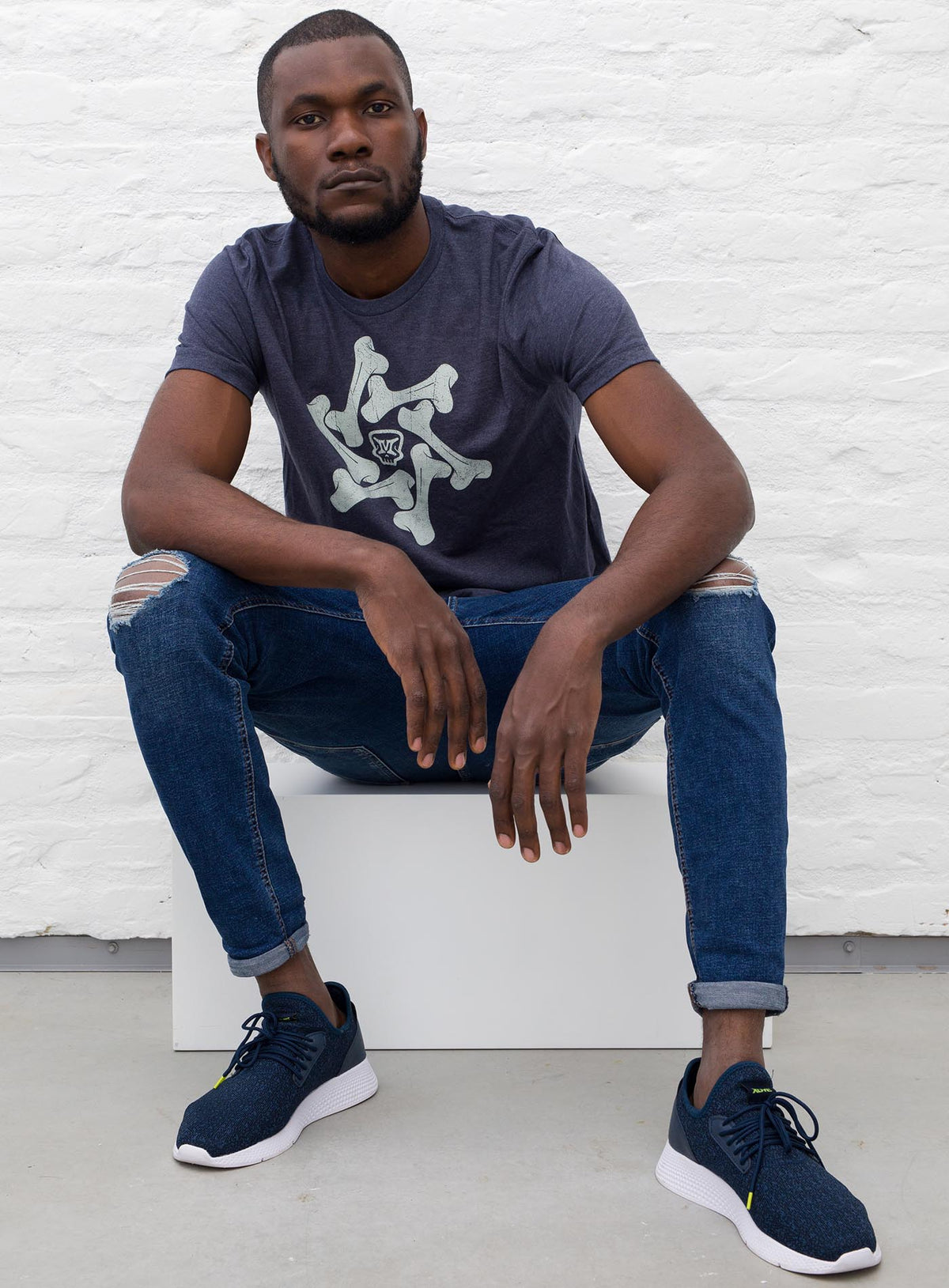 Man modeling a Heather blue unisex t-shirt featuring a front print of the Moghoul symbol surrounded by a star of bones.