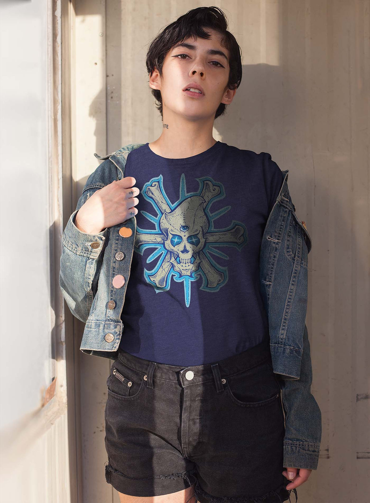 Female modeling a Heather blue unisex t-shirt featuring a front print of a three-bone alien Jolly Roger pirate illustration by G.M. Meave.