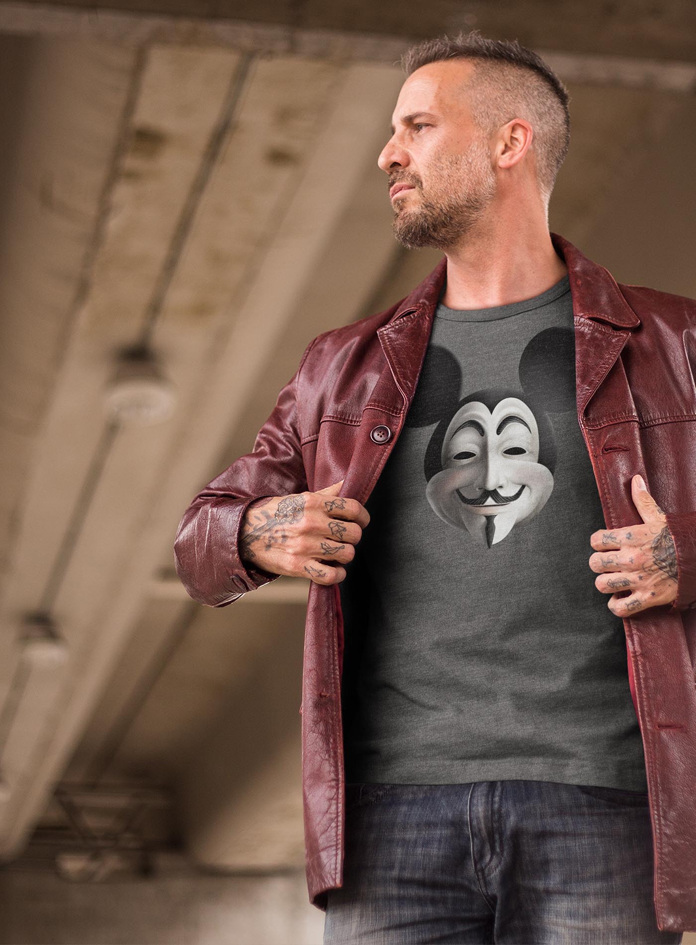 man modeling a heather grey unisex t-shirt featuring a front print fusing Mickey Mouse and Guy Fawkes.