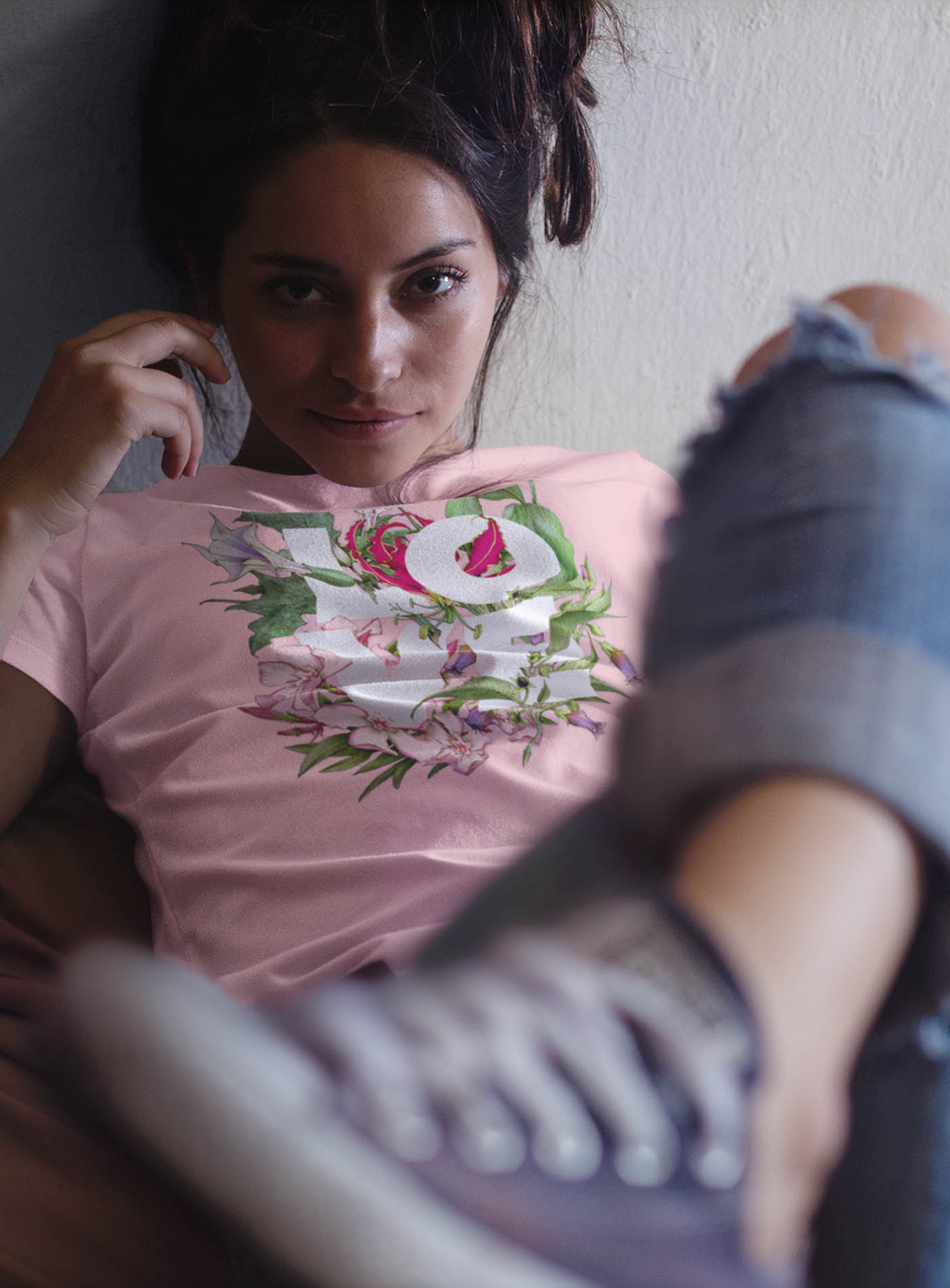 Female modeling a Pink unisex t-shirt featuring the word LOVE surrounded by poisonous flowers such as oleander, fire lily, belladonna and toloache.