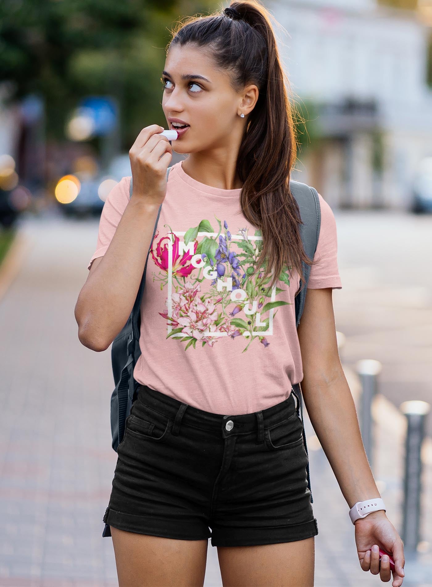 man modeling a Heather black unisex t-shirt featuring white Moghoul logo surrounded by poisonous flowers such as oleander, fire lily, belladonna and toloache.