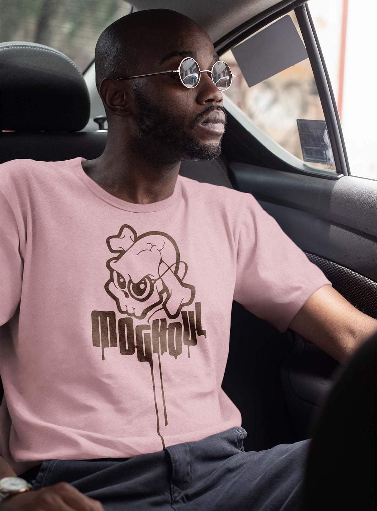 guy modeling a Pink unisex t-shirt featuring a yellow Mr. Shade Moghoul logo by G.M. Meave.