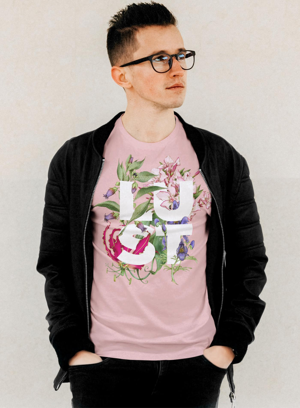 Man modeling a Detail of Heather pink unisex t-shirt featuring the word LUST surrounded by poisonous flowers such as oleander, fire lily, belladonna and toloache.