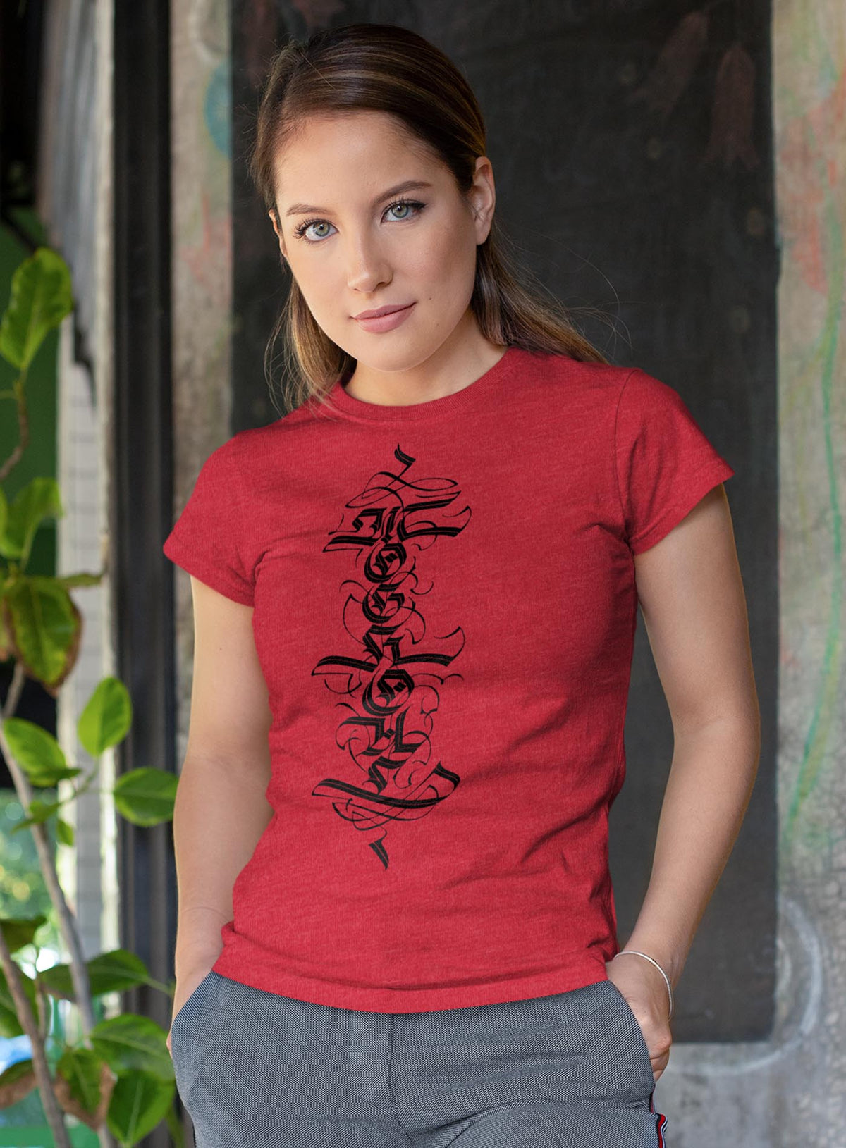 Female modeling a Heather red unisex t-shirt featuring a front print of a white Moghoul straight-up-gothic logo by Mexican typographer G.M. Meave.
