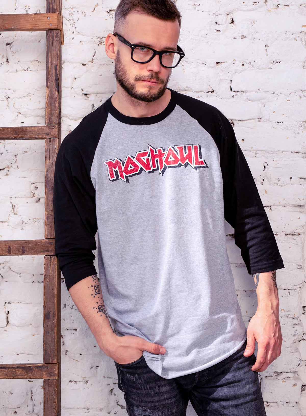 man modeling a 3/4 sleeves raglan t-shirt featuring a front print of the Moghoul logo in vintage 80&#39;s hair-band style.